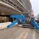 Spinnenraupenkran greift durch eine enge Öffnung ins Gebäude, beim Kran handelt es sich um ein Gerät von Unic