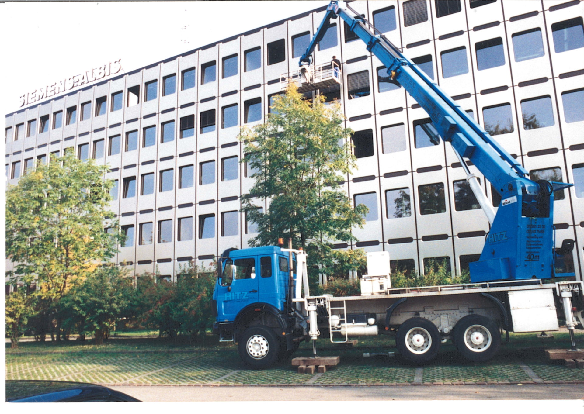 blaue LKW Arbeitsbühne im ausgefahrenen Zustand vor einer Metallfassade