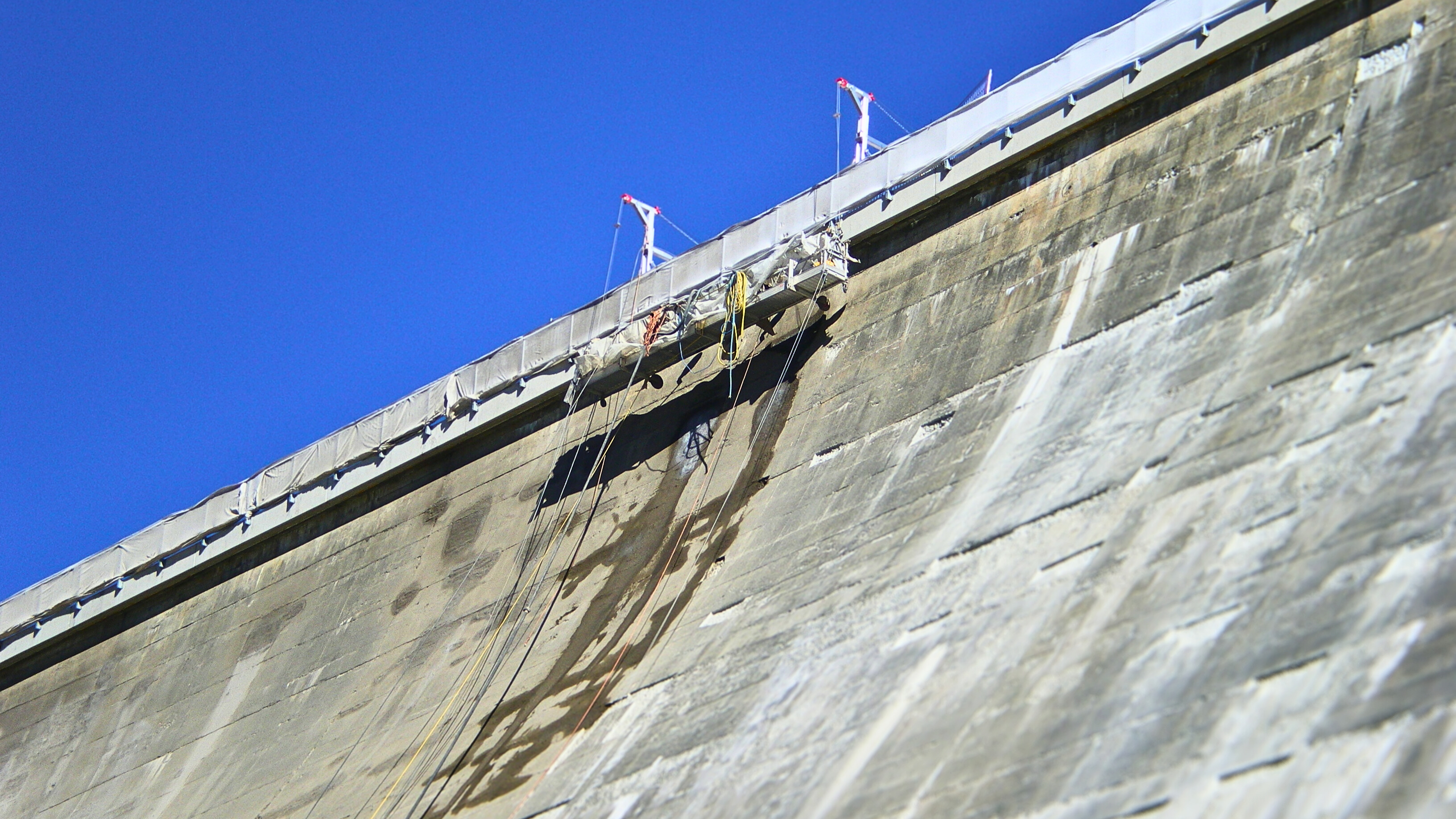 Gerüst an einer Staumauer, an Seilen befestigt